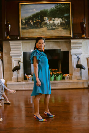 A woman in blue dress standing on the floor.