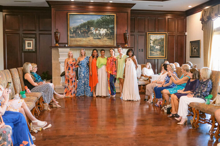 A group of women standing in front of a painting.