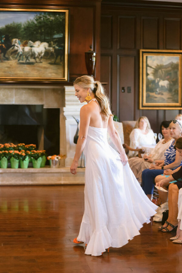 A woman in white dress walking down the runway.