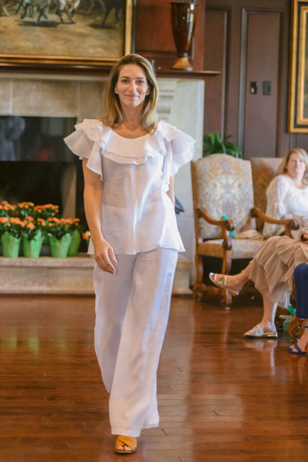 A woman in white outfit standing on wooden floor.