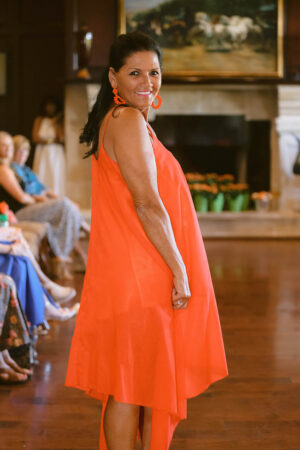 A woman in an orange dress standing on the floor.