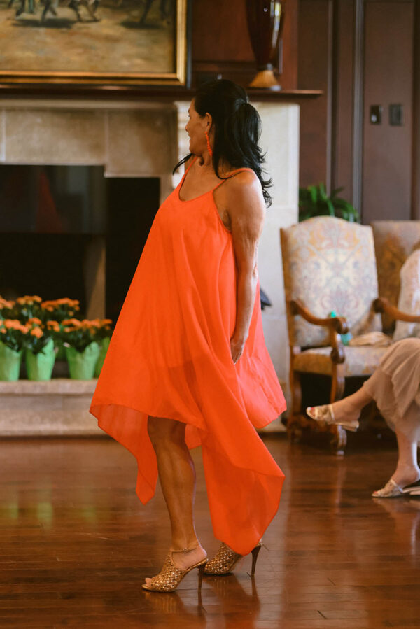 A woman in an orange dress standing on the floor.