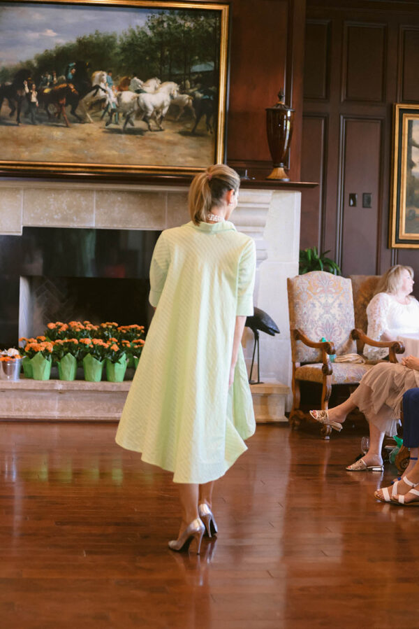 A woman in a green dress standing on the floor.