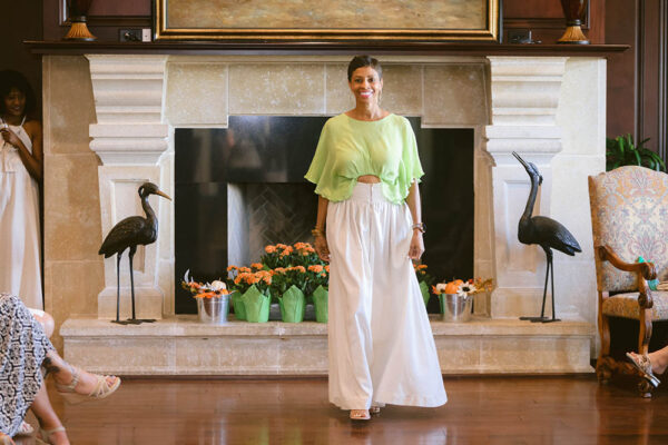 A woman in white pants and green top standing on the floor.