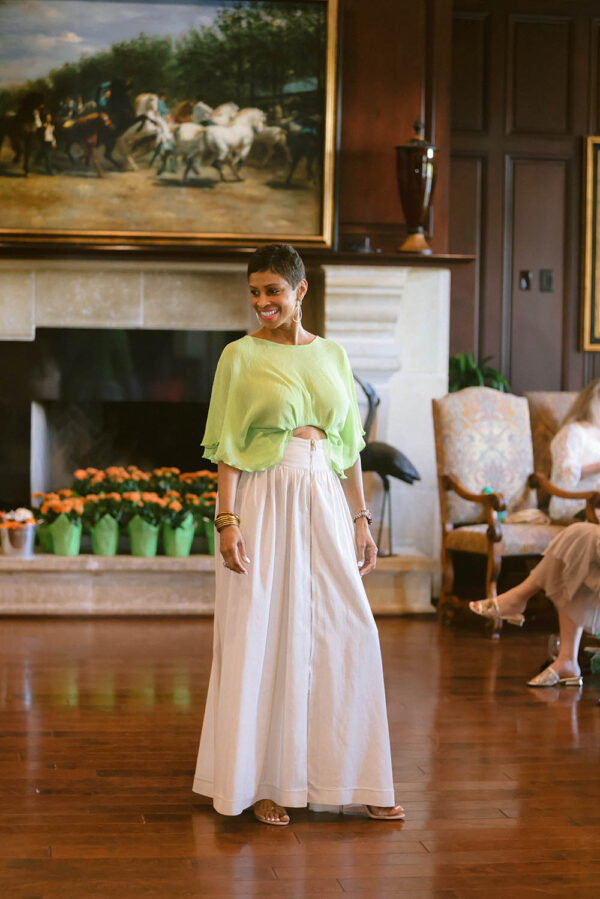 A woman in a green top and white skirt.