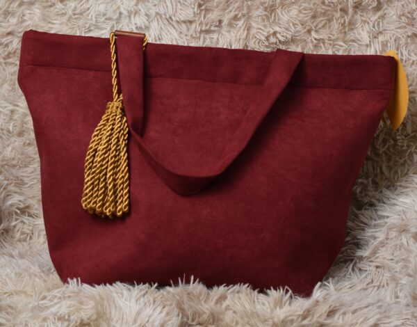 A red purse with a gold tassel hanging from the handle.