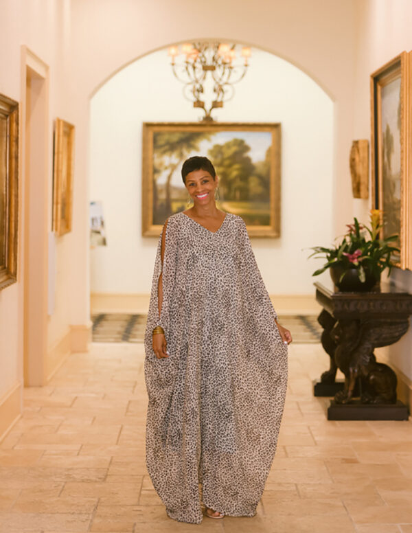 A woman in an ornate dress standing inside of a room.