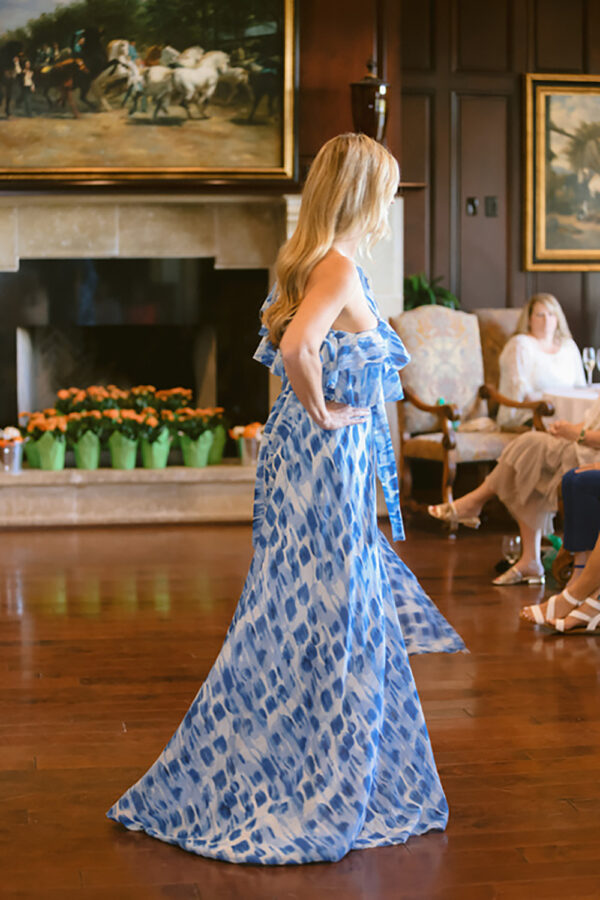 A woman in blue dress standing on wooden floor.