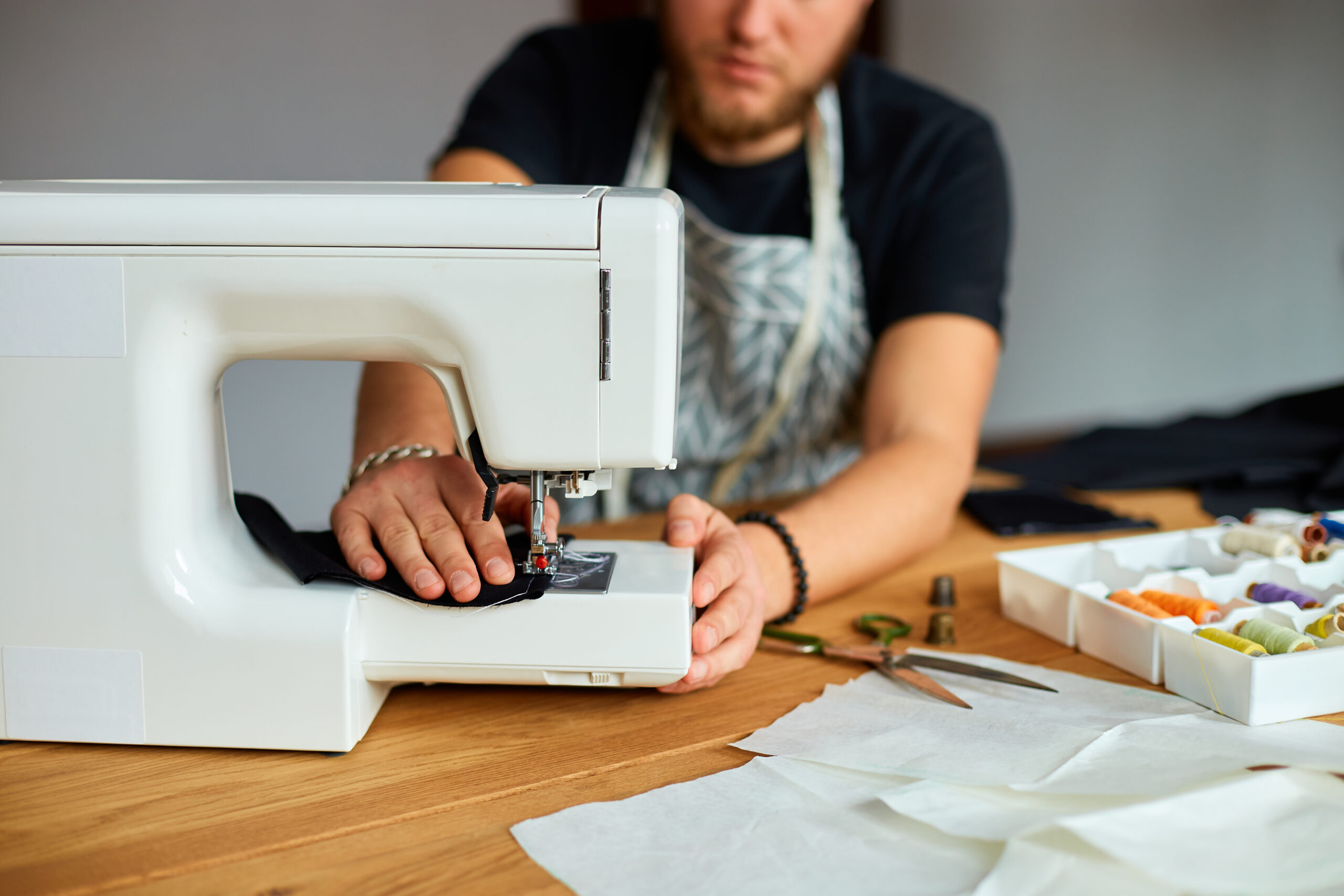 Man sews clothes on sewing machine inside a room