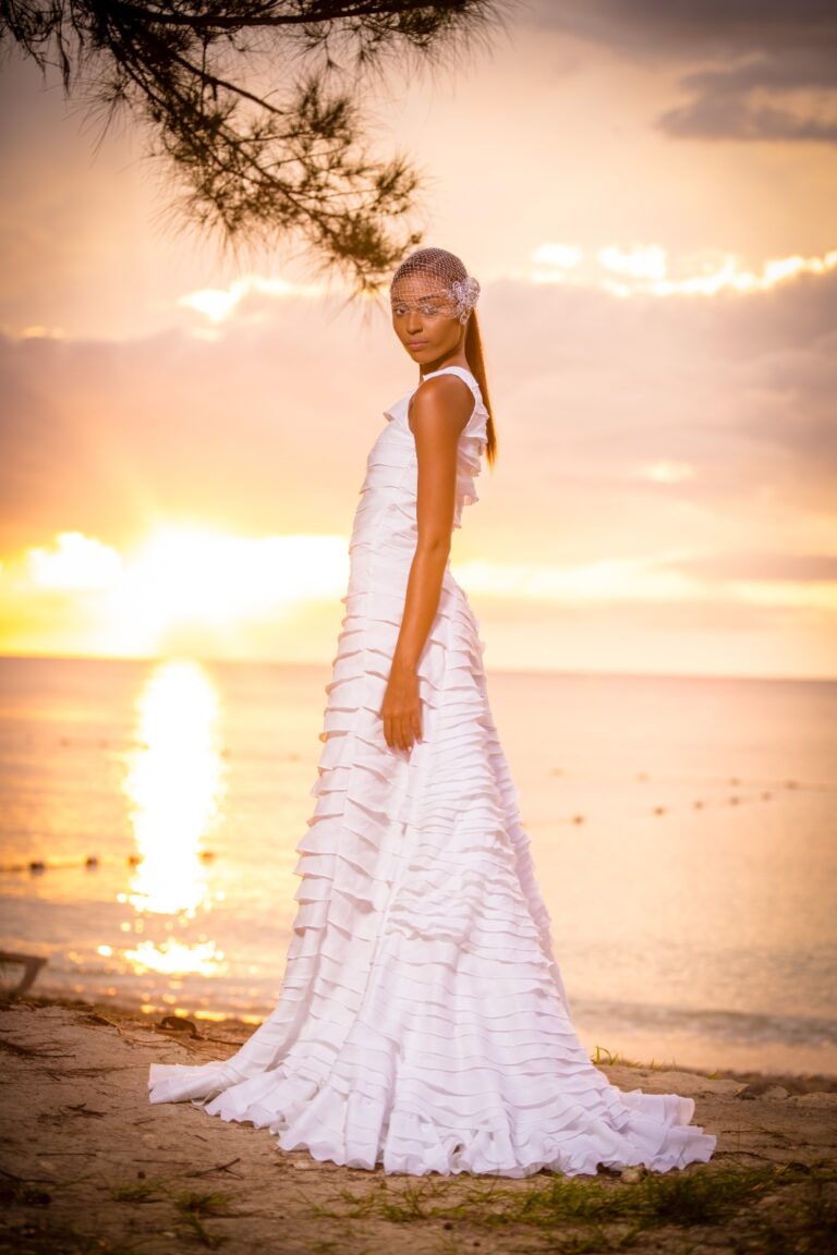 A young girl in white dress standing on beach.